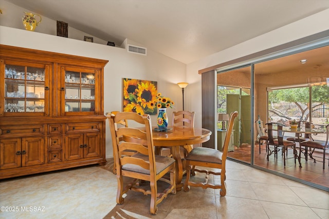 dining room with visible vents, vaulted ceiling, and light tile patterned floors