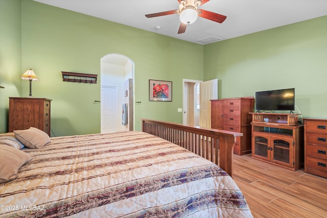 bedroom with arched walkways, wood finished floors, a ceiling fan, and visible vents