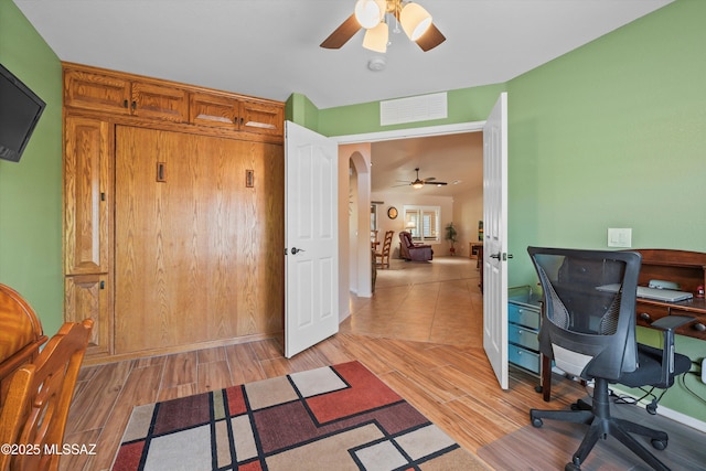 office area featuring arched walkways, ceiling fan, visible vents, and light wood-style floors