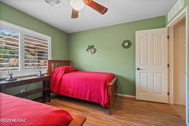 bedroom with visible vents, baseboards, ceiling fan, and wood finished floors