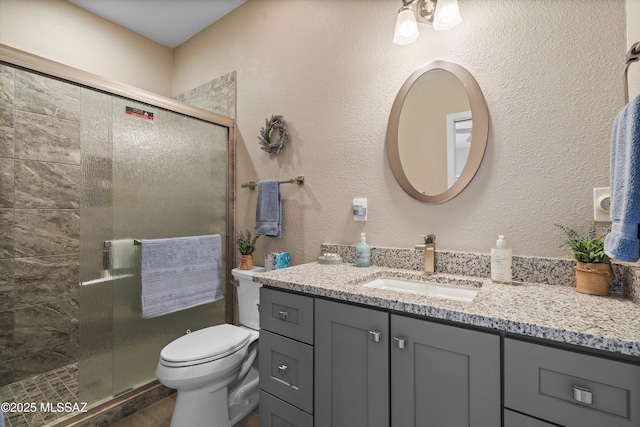 full bathroom featuring a shower stall, vanity, toilet, and wood finished floors