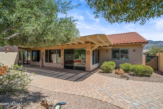 back of house with a patio area, stucco siding, fence, and a tile roof