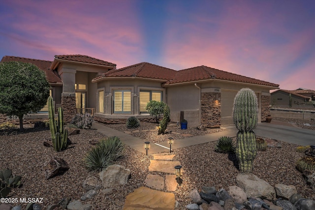 mediterranean / spanish home with a garage, driveway, stucco siding, and a tile roof