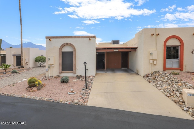 southwest-style home featuring concrete driveway, a mountain view, and stucco siding