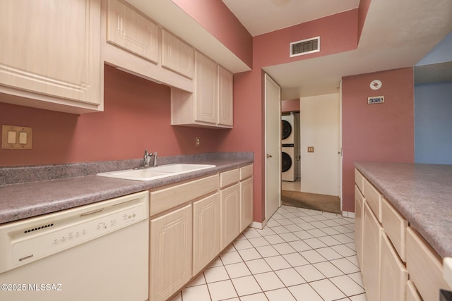kitchen featuring stacked washer / dryer, dishwasher, visible vents, light tile patterned floors, and a sink
