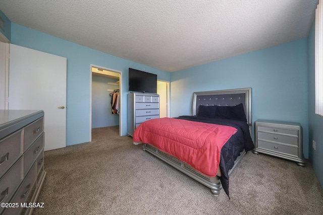 bedroom with a spacious closet, carpet flooring, and a textured ceiling