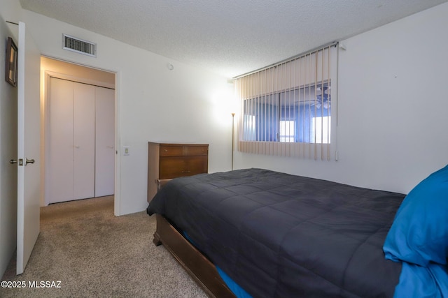 carpeted bedroom with visible vents and a textured ceiling