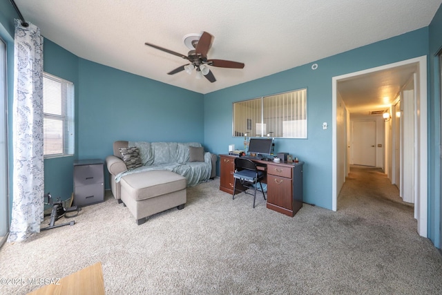carpeted office space featuring vaulted ceiling and a ceiling fan