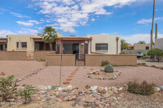 adobe home with stucco siding, a gate, and a fenced front yard