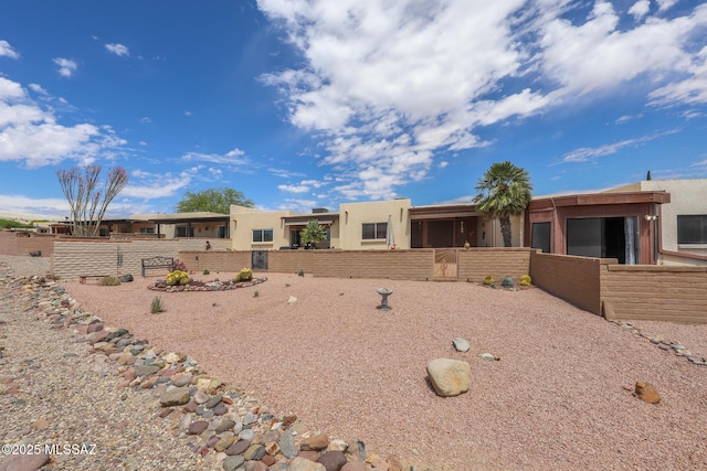 pueblo revival-style home with fence private yard and stucco siding