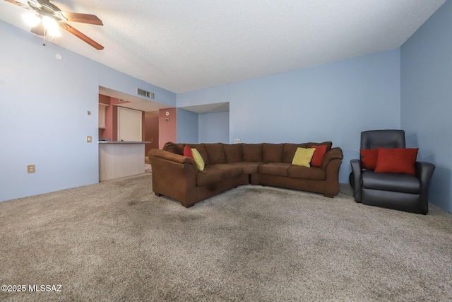 living room featuring a ceiling fan, visible vents, a textured ceiling, and carpet flooring