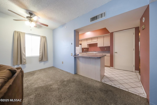 kitchen featuring visible vents, a ceiling fan, a sink, light colored carpet, and open floor plan
