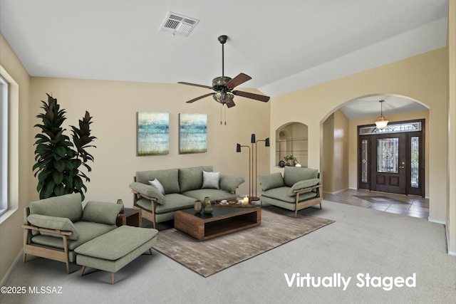 living room with arched walkways, a ceiling fan, visible vents, carpet floors, and baseboards