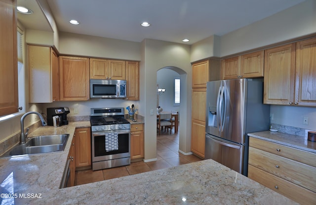 5200 E Calle Vista De Colores, Tucson, AZ 85711 - kitchen featuring stainless steel appliances, a sink, tile patterned flooring, arched walkways, and light stone counters