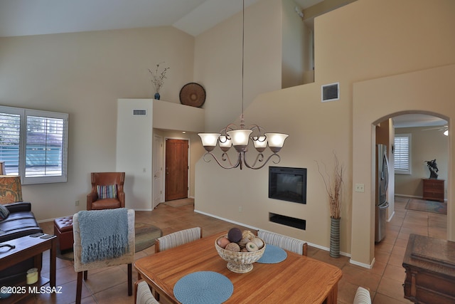 5200 E Calle Vista De Colores, Tucson, AZ 85711 - dining room featuring light tile patterned floors, arched walkways, a chandelier, high vaulted ceiling, and baseboards