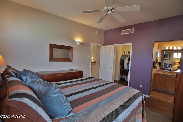 5200 E Calle Vista De Colores, Tucson, AZ 85711 - bedroom with dark wood-style floors, a walk in closet, connected bathroom, a closet, and baseboards