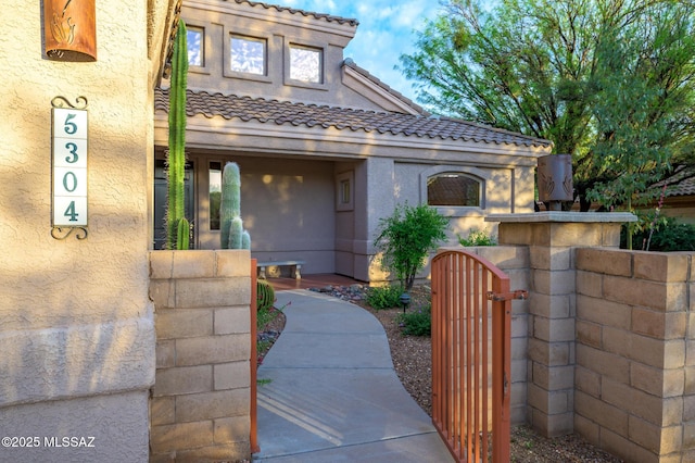 mediterranean / spanish-style house featuring a gate, stucco siding, a tile roof, and fence