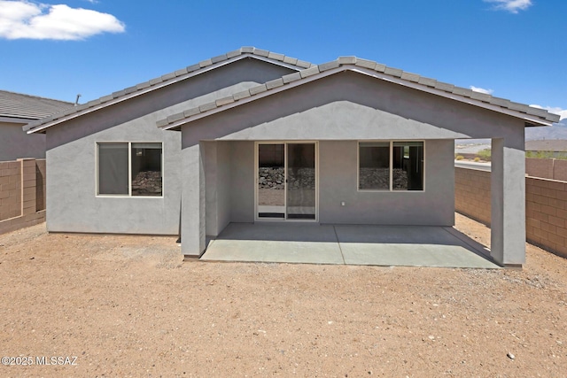 rear view of house featuring a fenced backyard, a patio, and stucco siding