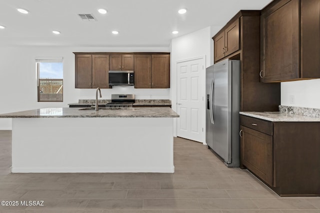 kitchen with visible vents, dark brown cabinetry, light stone counters, and stainless steel appliances