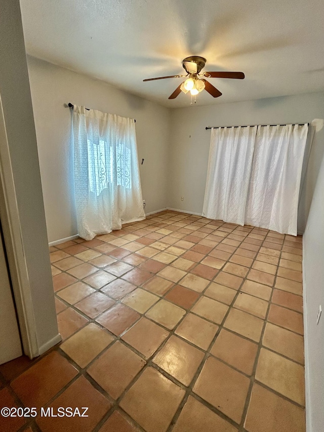 spare room featuring baseboards, light tile patterned floors, and ceiling fan