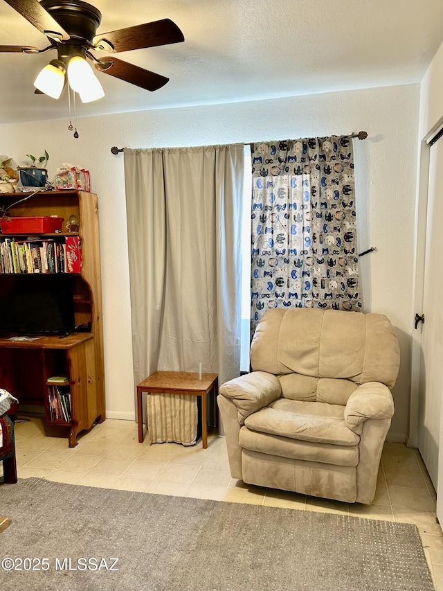 sitting room featuring ceiling fan and tile patterned flooring
