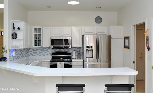 kitchen with a breakfast bar area, appliances with stainless steel finishes, and decorative backsplash
