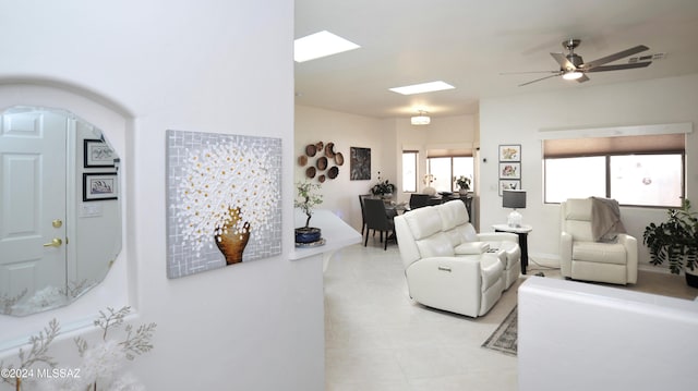 living area featuring a ceiling fan, arched walkways, visible vents, and a skylight