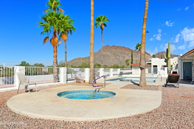 pool featuring fence, a mountain view, a hot tub, and a patio