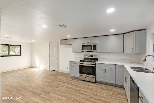 kitchen featuring recessed lighting, gray cabinetry, visible vents, appliances with stainless steel finishes, and a sink