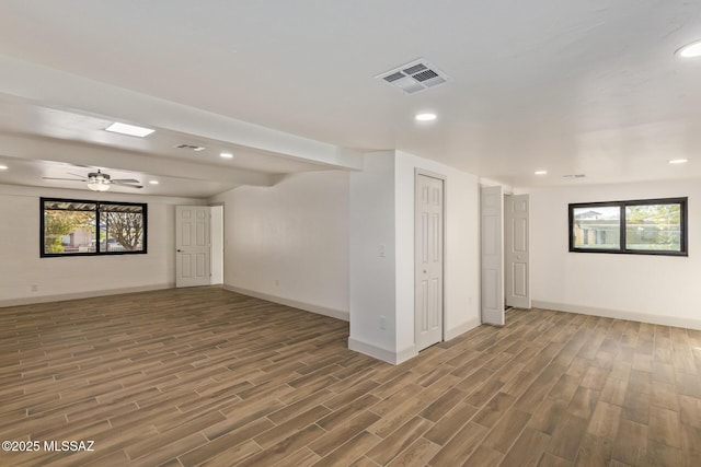 spare room featuring plenty of natural light, visible vents, baseboards, and wood finished floors