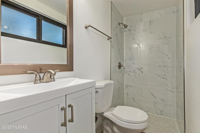 full bathroom with toilet, vanity, and a tile shower