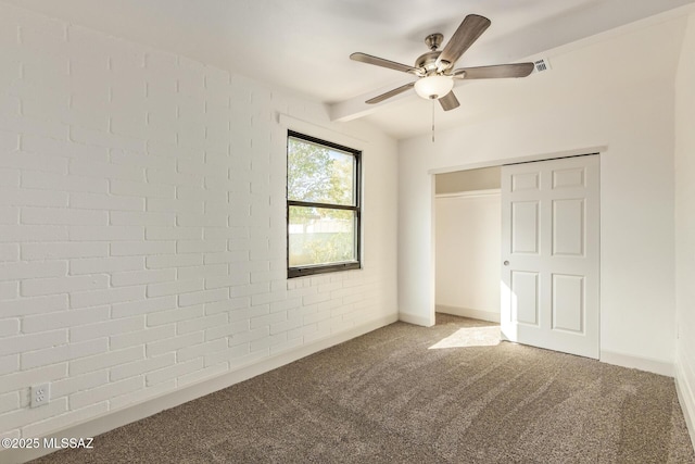 unfurnished bedroom with baseboards, a closet, brick wall, a ceiling fan, and carpet floors