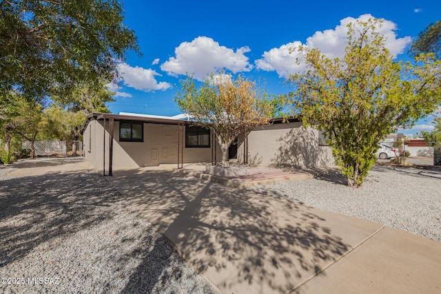 view of front of property with a patio area, concrete block siding, and fence