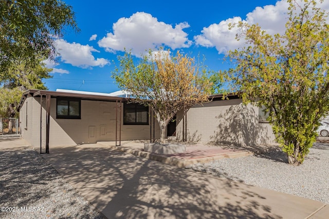view of front of house with a patio area and concrete block siding