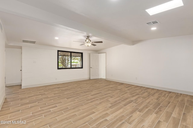 spare room featuring light wood-type flooring, baseboards, beam ceiling, and visible vents