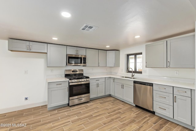 kitchen with a sink, visible vents, light wood-type flooring, and stainless steel appliances