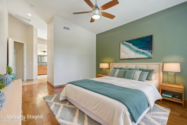bedroom featuring wood finished floors, high vaulted ceiling, ceiling fan, and visible vents