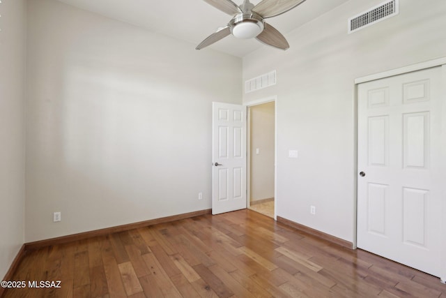 unfurnished bedroom featuring a towering ceiling, visible vents, and hardwood / wood-style flooring