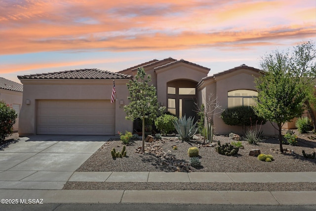 view of front facade with a garage, driveway, stucco siding, and a tile roof