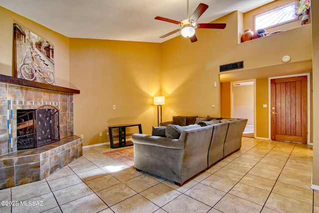 living room featuring ceiling fan, visible vents, a tiled fireplace, and light tile patterned floors