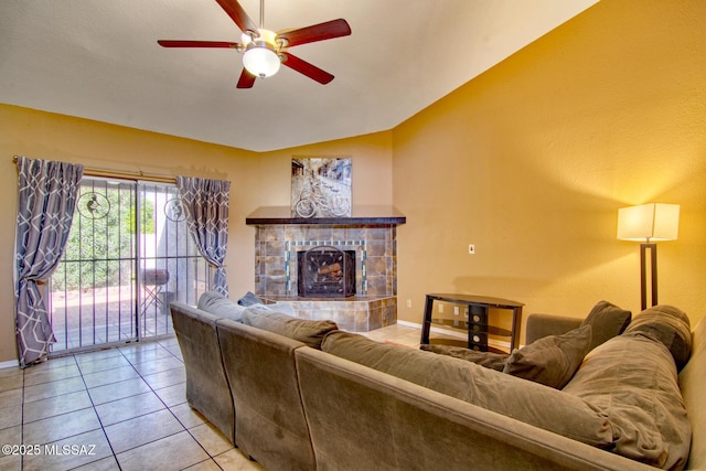 living room featuring a ceiling fan, a tile fireplace, baseboards, and light tile patterned floors
