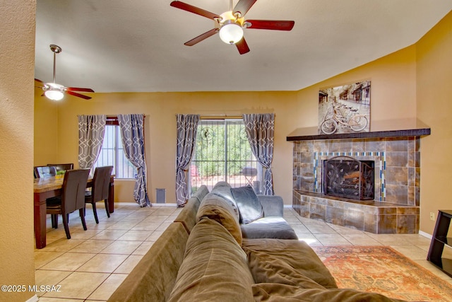 tiled living area with a fireplace, ceiling fan, and baseboards