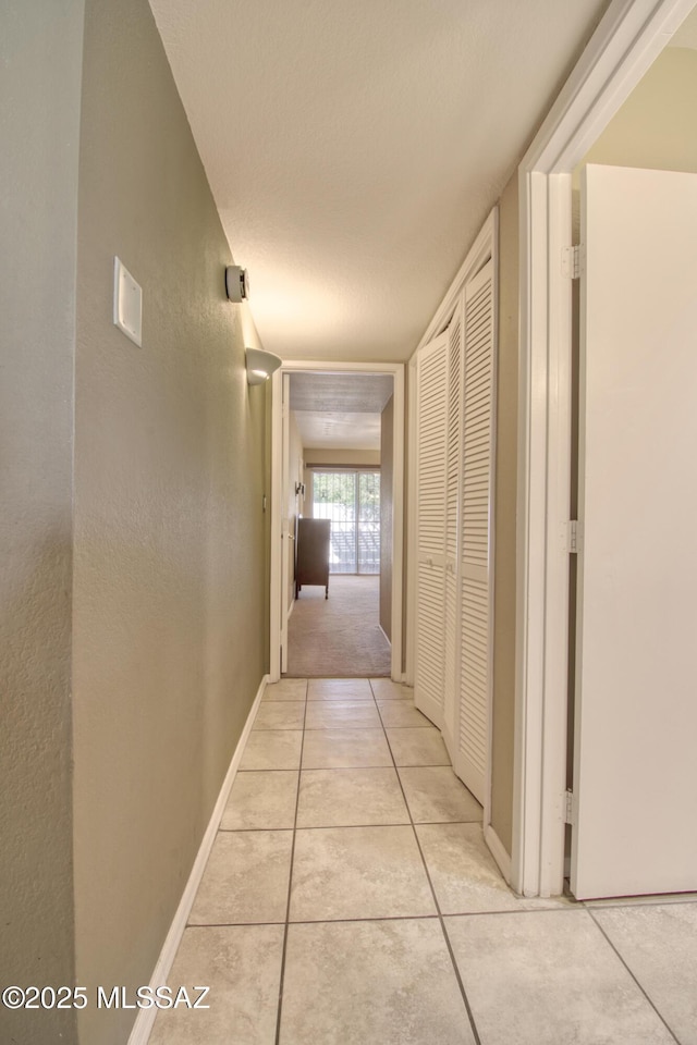 hallway with light tile patterned floors and baseboards
