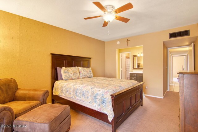 bedroom with baseboards, ensuite bath, visible vents, a ceiling fan, and light carpet