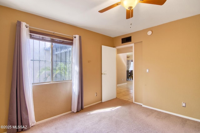spare room featuring baseboards, visible vents, carpet floors, and a ceiling fan