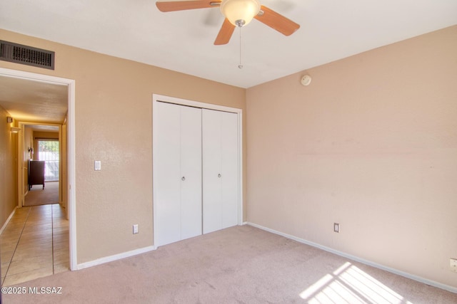 unfurnished bedroom with baseboards, ceiling fan, visible vents, light carpet, and a closet