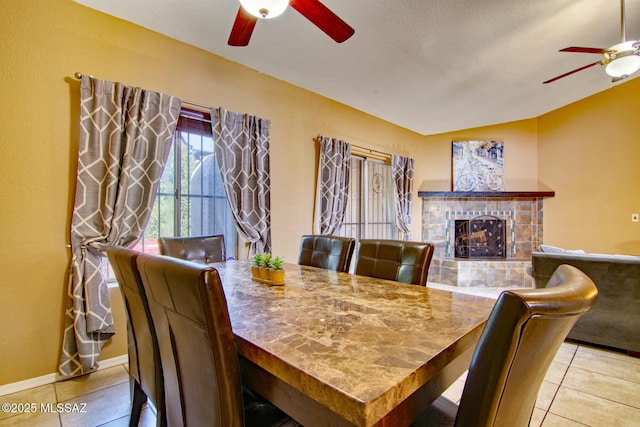 dining room with a ceiling fan, tile patterned floors, and a fireplace