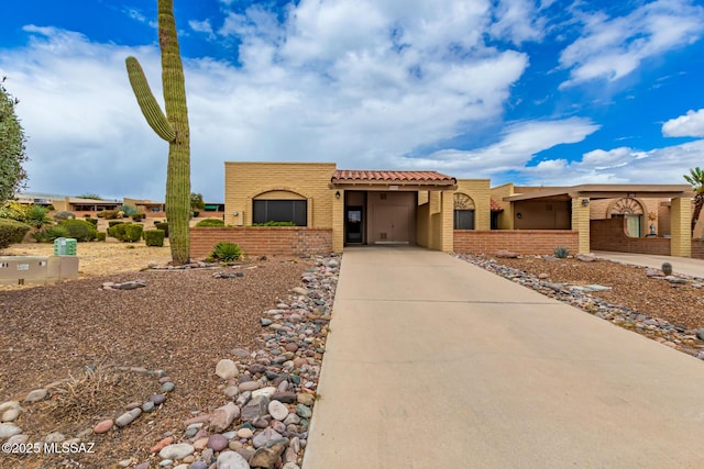 pueblo-style house featuring brick siding, driveway, and stucco siding