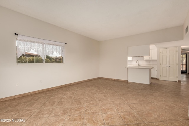 unfurnished living room with baseboards, visible vents, a sink, and light tile patterned floors