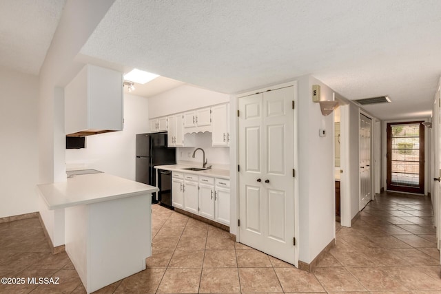 kitchen with light countertops, a sink, white cabinetry, a peninsula, and black appliances